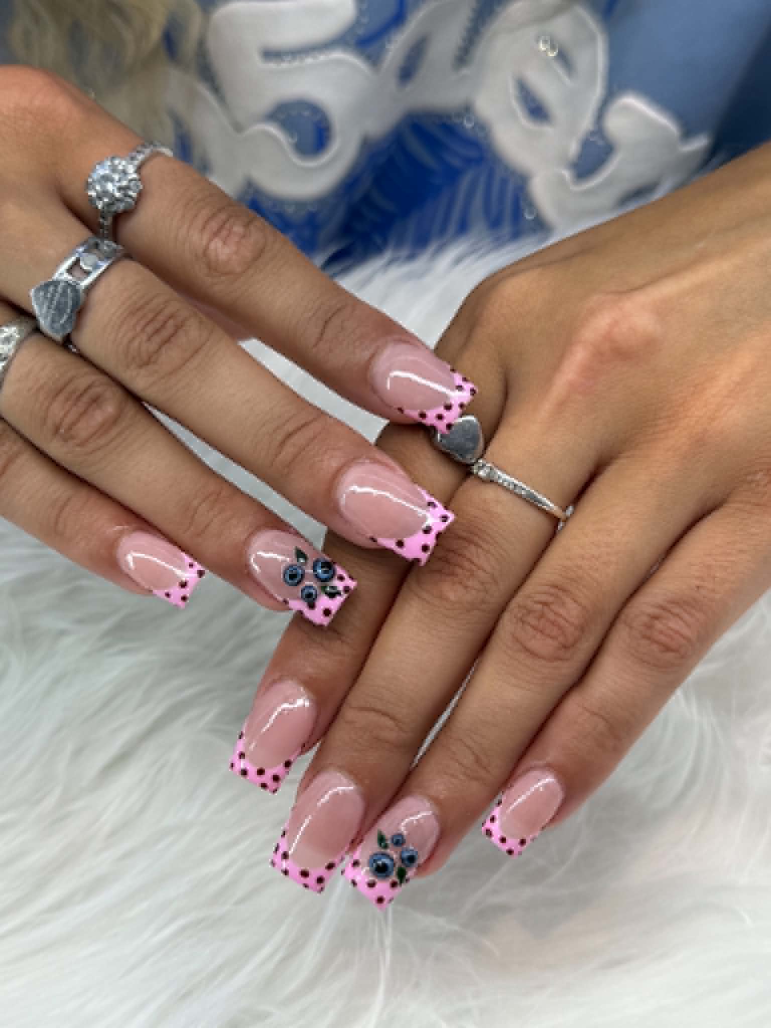 Pink French tips with black polka dots and blue flower accents